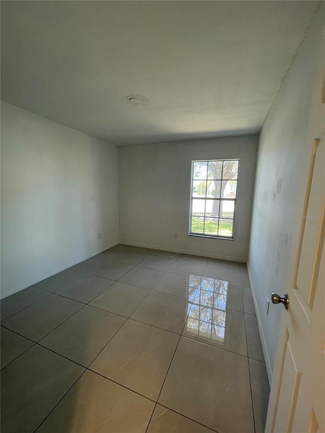 unfurnished room with light tile patterned floors and baseboards