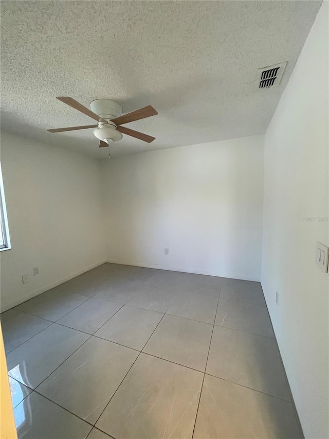 spare room featuring tile patterned flooring, visible vents, a textured ceiling, and ceiling fan