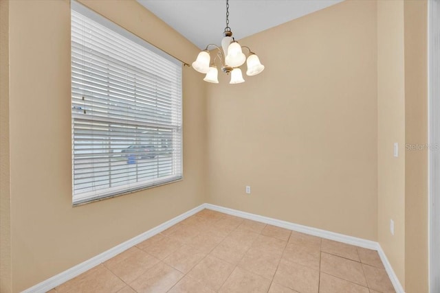 tiled spare room with a chandelier