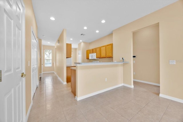 kitchen with light tile patterned floors, light brown cabinetry, and kitchen peninsula