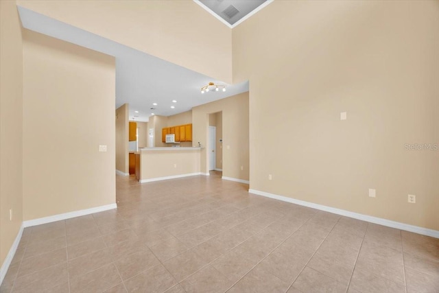 spare room featuring light tile patterned floors, crown molding, and a high ceiling