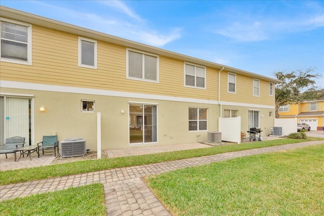 rear view of house featuring central AC unit, a yard, and a patio area