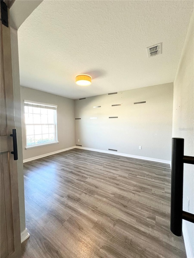 unfurnished room with wood-type flooring and a textured ceiling