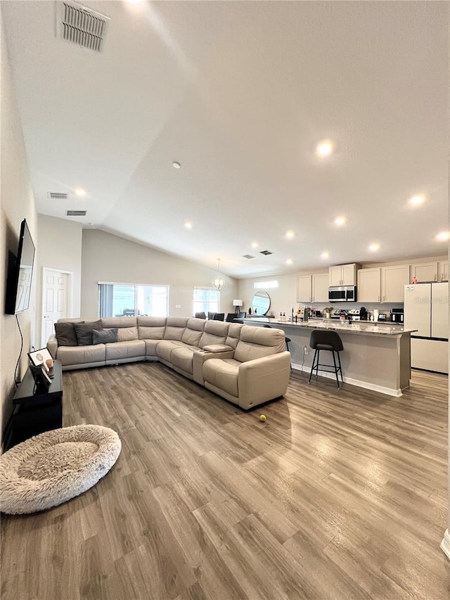 living room featuring lofted ceiling and light hardwood / wood-style flooring