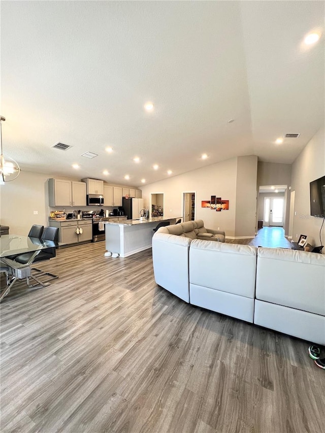 living room with vaulted ceiling and light wood-type flooring