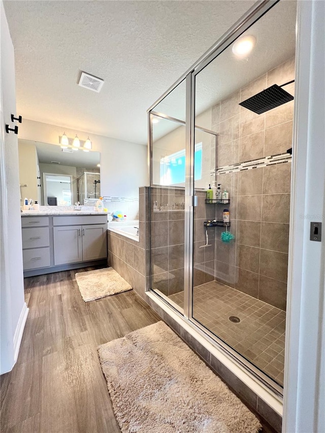 bathroom with hardwood / wood-style floors, vanity, separate shower and tub, and a textured ceiling