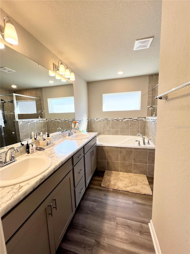 bathroom with hardwood / wood-style flooring, vanity, a healthy amount of sunlight, and plus walk in shower