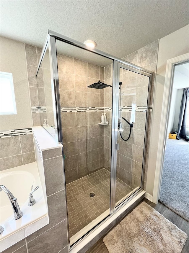 bathroom with plus walk in shower, hardwood / wood-style floors, and a textured ceiling