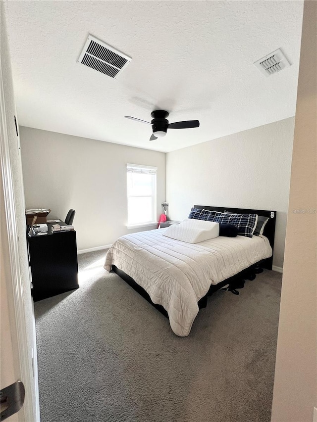 carpeted bedroom featuring ceiling fan and a textured ceiling