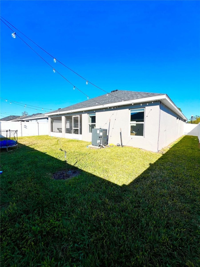 rear view of property featuring a lawn and central AC unit