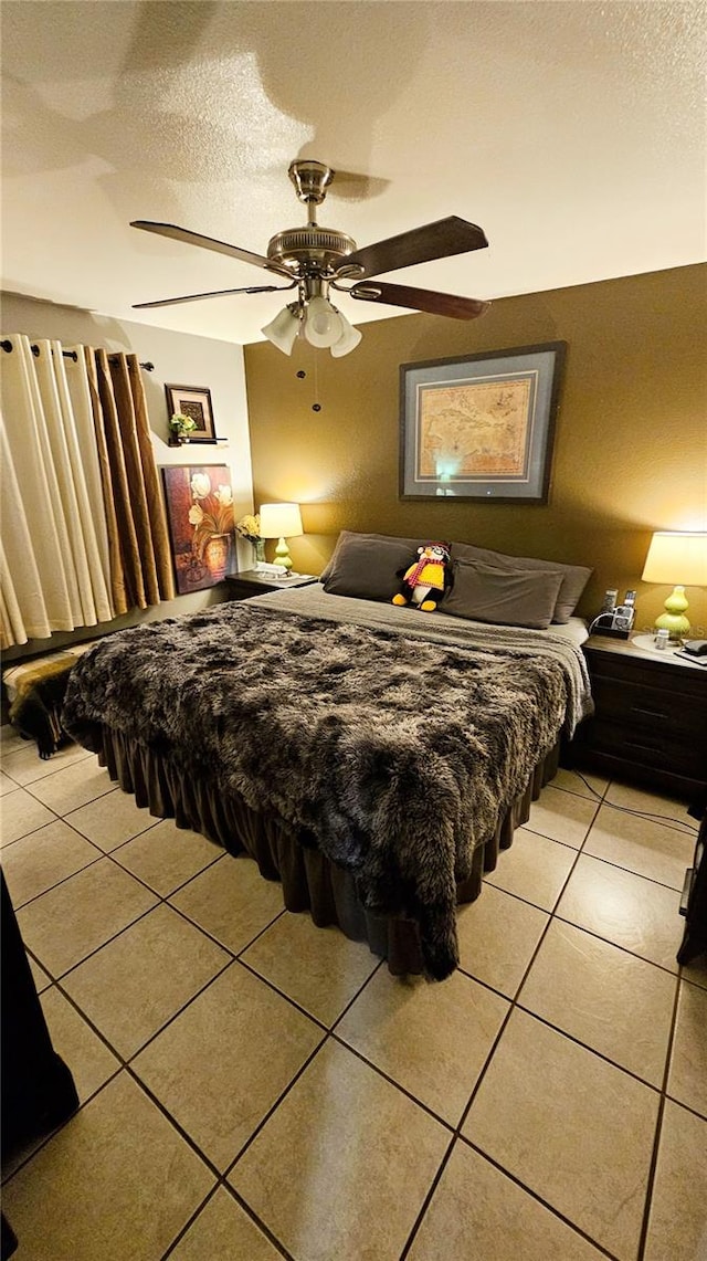 bedroom featuring ceiling fan, light tile patterned flooring, and a textured ceiling