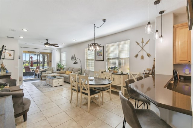 tiled dining space featuring ceiling fan with notable chandelier