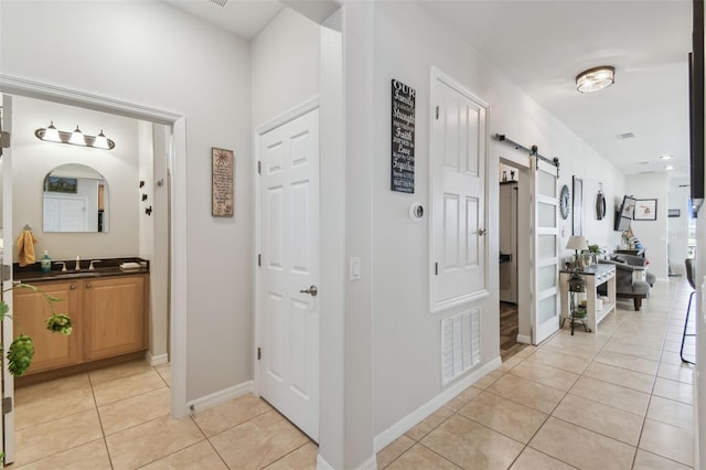 hall featuring sink, a barn door, and light tile patterned floors