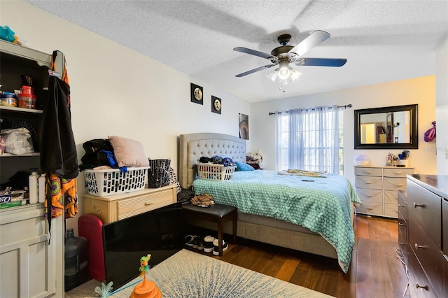 bedroom featuring ceiling fan, dark wood-type flooring, and a textured ceiling