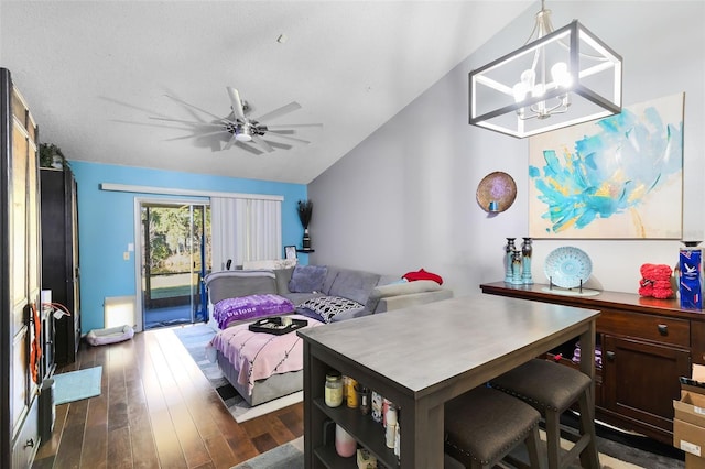 dining area with ceiling fan with notable chandelier, vaulted ceiling, and dark hardwood / wood-style floors