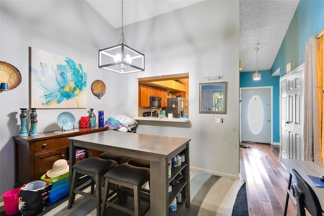 dining space featuring lofted ceiling, a textured ceiling, and an inviting chandelier