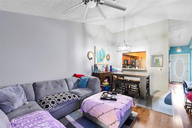 living room with a textured ceiling, ceiling fan, hardwood / wood-style floors, and lofted ceiling