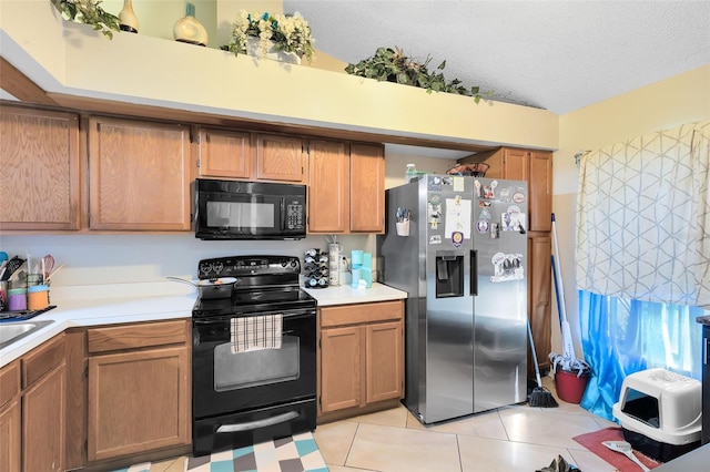 kitchen with sink, light tile patterned floors, a textured ceiling, and black appliances