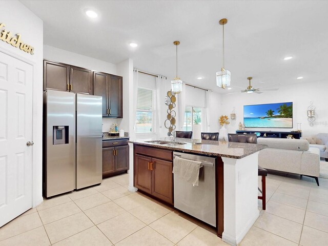 kitchen featuring stone counters, ceiling fan, sink, stainless steel appliances, and decorative light fixtures