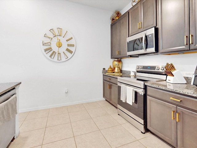 kitchen featuring light stone countertops, dark brown cabinets, light tile patterned floors, and appliances with stainless steel finishes