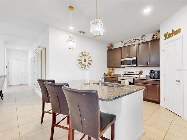 kitchen with sink, hanging light fixtures, a breakfast bar, light tile patterned floors, and appliances with stainless steel finishes