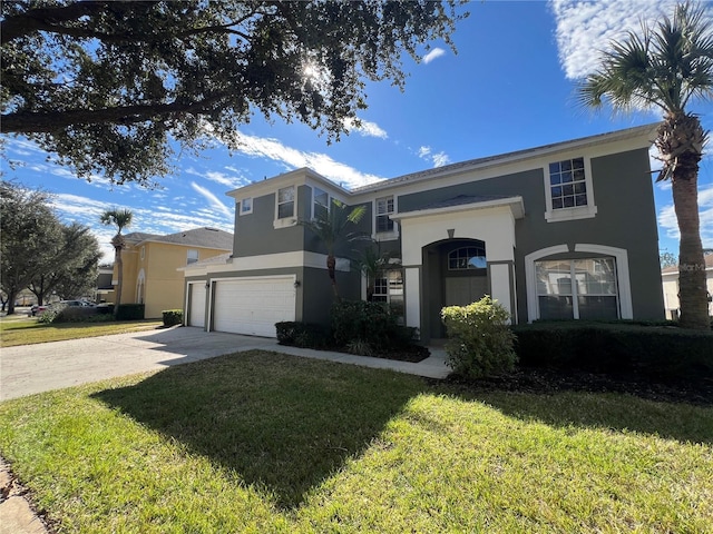 traditional-style home featuring an attached garage, a front yard, concrete driveway, and stucco siding