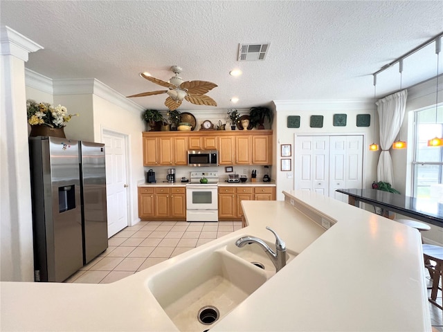 kitchen featuring visible vents, stainless steel appliances, crown molding, a sink, and light tile patterned flooring