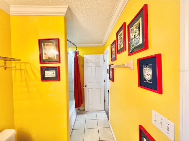 corridor with light tile patterned floors, a textured ceiling, and crown molding