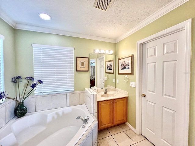 bathroom featuring tiled tub, vanity, ornamental molding, a textured ceiling, and tile patterned floors