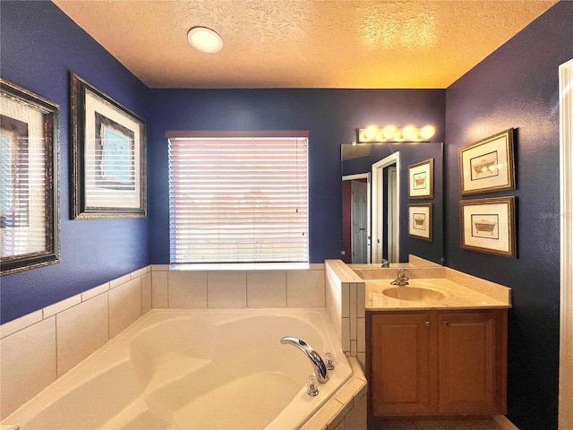 bathroom featuring vanity, a relaxing tiled tub, and a textured ceiling