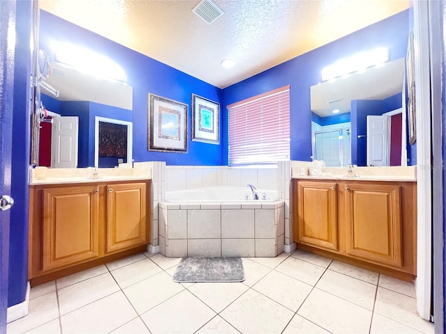 full bath with a sink, tile patterned flooring, a garden tub, and visible vents