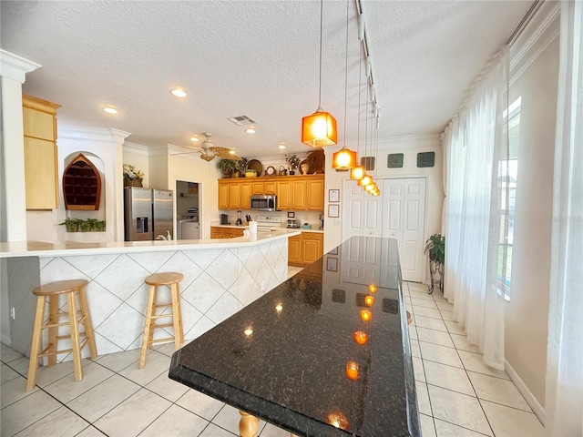 8557 La Isla Dr, Kissimmee, FL 34747 - kitchen featuring appliances with stainless steel finishes, a kitchen breakfast bar, light tile patterned floors, healthy amount of natural light, and ornamental molding