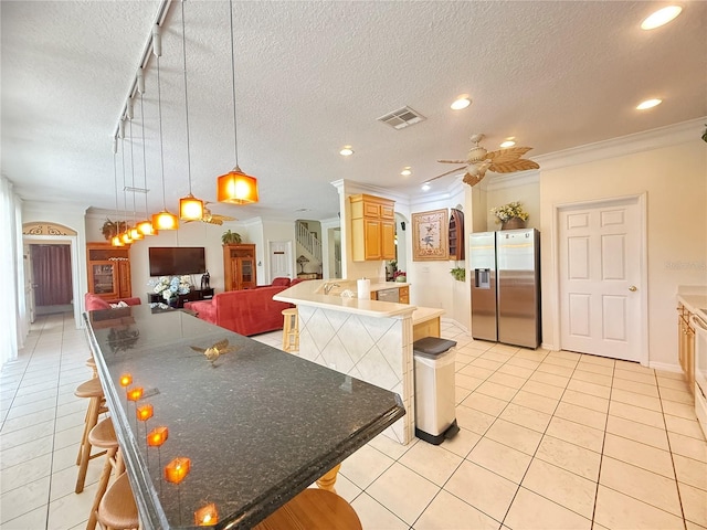8557 La Isla Dr, Kissimmee, FL 34747 - kitchen with stainless steel fridge, a textured ceiling, a breakfast bar, crown molding, and ceiling fan