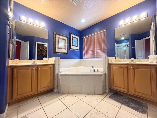 8557 La Isla Dr, Kissimmee, FL 34747 - full bathroom featuring a textured ceiling, a garden tub, two vanities, a stall shower, and tile patterned flooring