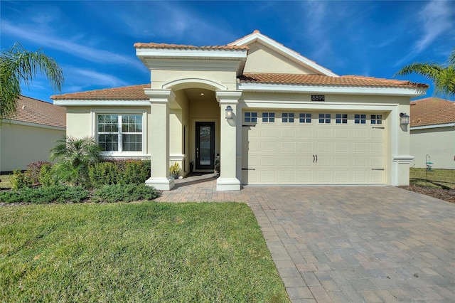 mediterranean / spanish home featuring a front lawn and a garage