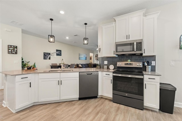 kitchen with kitchen peninsula, sink, stainless steel appliances, and white cabinetry