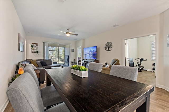 dining space with ceiling fan and light hardwood / wood-style flooring