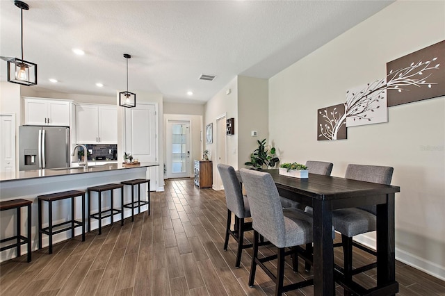 dining space featuring dark wood-type flooring, sink, and a textured ceiling