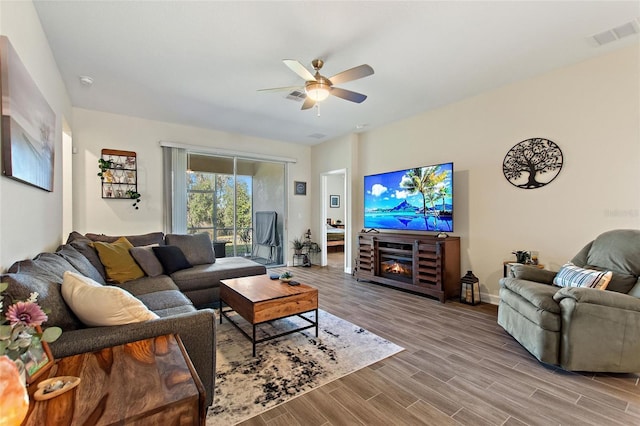 living room with ceiling fan, a fireplace, and wood-type flooring