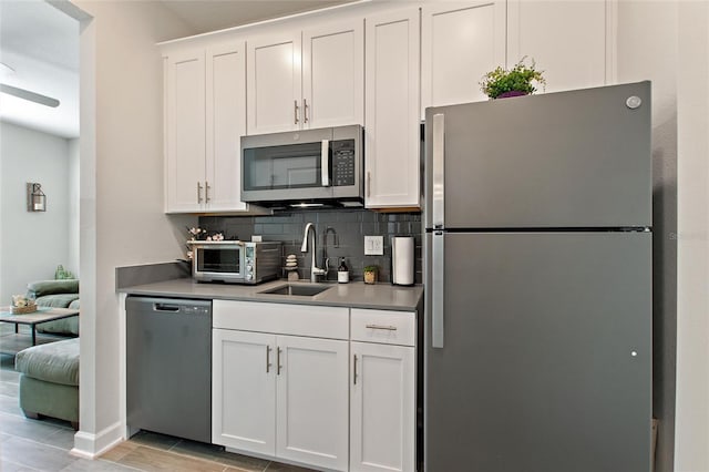 kitchen featuring decorative backsplash, sink, white cabinetry, and appliances with stainless steel finishes