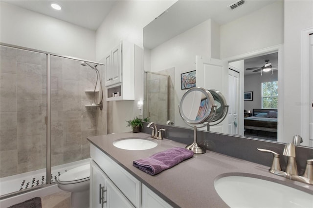 bathroom featuring toilet, ceiling fan, a shower with shower door, and vanity