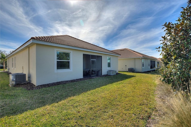 rear view of house featuring a lawn and central AC