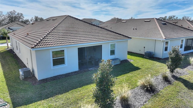 rear view of house featuring a lawn and central AC