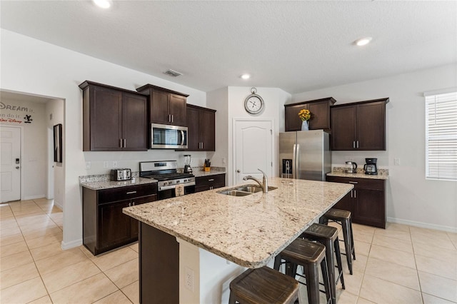 kitchen featuring appliances with stainless steel finishes, sink, a kitchen bar, a kitchen island with sink, and light tile patterned floors