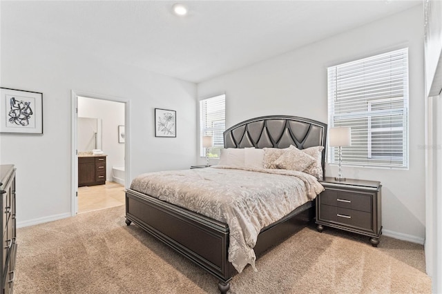 bedroom with connected bathroom and light carpet