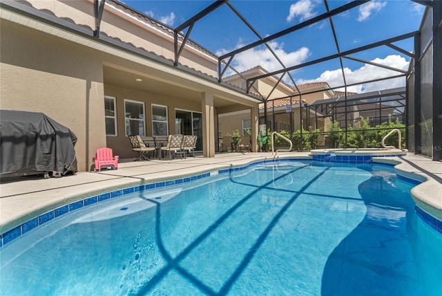 view of pool with an in ground hot tub, grilling area, a patio area, and glass enclosure