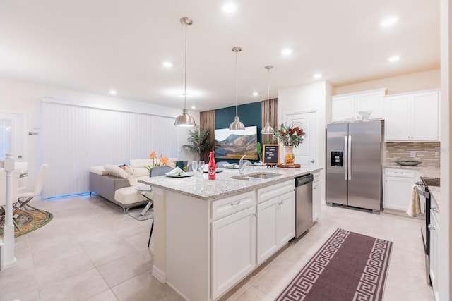 kitchen with sink, hanging light fixtures, a kitchen island with sink, white cabinets, and appliances with stainless steel finishes