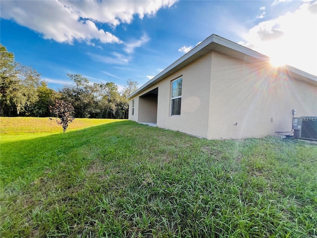 view of side of home featuring a lawn and cooling unit