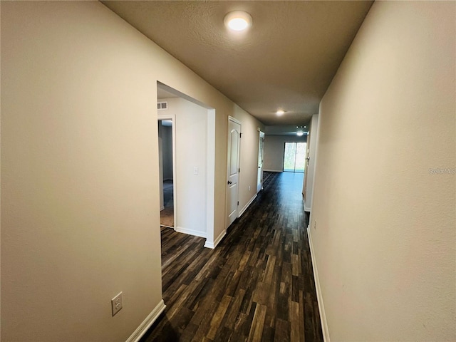 hall featuring a textured ceiling and dark hardwood / wood-style floors