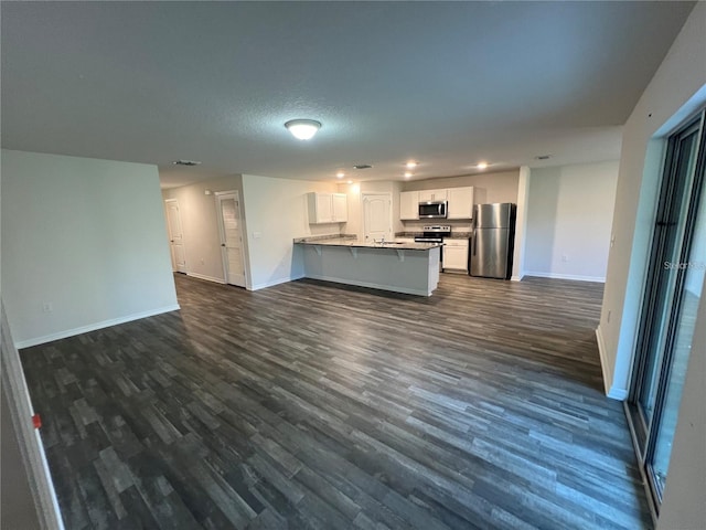 kitchen with dark wood-type flooring, a textured ceiling, white cabinetry, kitchen peninsula, and stainless steel appliances